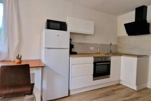a kitchen with white cabinets and a white refrigerator at Appartement en bord de mer 2 in Banyuls-sur-Mer
