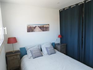um quarto com uma cama com cortinas azuis em Appartement indépendant avec terrasse à 200m de la plage em Canet-en-Roussillon