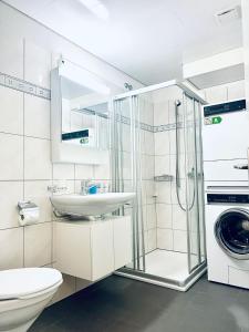 a bathroom with a sink and a washing machine at Gauencenter EG - CharmingStay in Flums