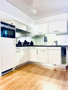 a kitchen with white cabinets and a wooden floor at Gauencenter EG - CharmingStay in Flums