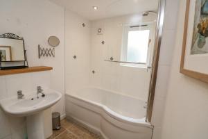 a bathroom with a bath tub and a sink at The Loft Cottage in Totnes