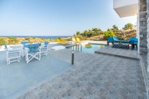 a patio with a table and chairs next to a pool at Ciel Blue Villas in Kiotari