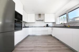 a kitchen with white cabinets and a wooden floor at Luxury Oceanview Villa with Private Pool in Ericeira