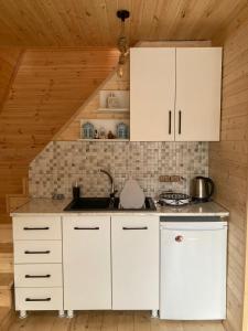 - une cuisine avec des placards blancs et un évier dans l'établissement ლენტეხის მთის სასტუმრო - Lentekhi Mountain Inn, à Lentekhi