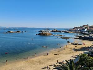 eine Gruppe von Menschen am Strand im Wasser in der Unterkunft Ático con piscina en palmeira in Ribeira