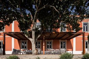 un edificio con un árbol delante de él en Central Villa en Sesimbra