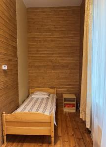 a small bedroom with a bed and a wooden wall at Võhma Külamaja in Võhma