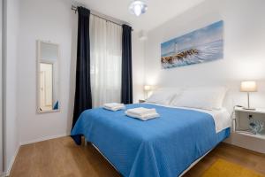 um quarto com uma cama azul e um cobertor azul em Apartmani Mundo em Ston