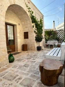 un patio de piedra con un banco y un tronco de árbol en Trulli Balè en Locorotondo