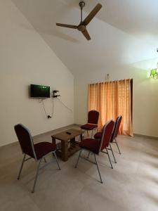 una sala da pranzo con sedie, tavolo e ventilatore a soffitto di Casita Greenacres Homestay a Vythiri