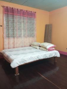 een bed in een kamer met een gordijn bij Camp Jenil Serenity Homestay in Malabuñgan