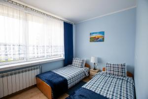 noclegi u zabki في إوك: سريرين في غرفة بجدران زرقاء ونافذة