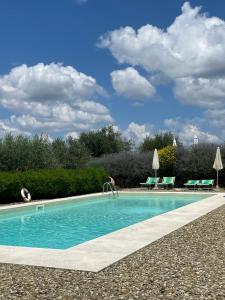 uma piscina com água azul e algumas cadeiras em Torre Di Ponzano em Barberino di Val dʼElsa