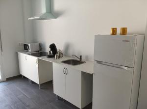 a white kitchen with a sink and a refrigerator at PENSION IRATI in Rincón de Soto