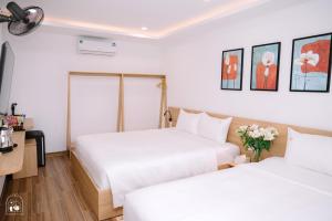 two beds in a hotel room with white walls at Chi's Homestay & Coffee in Hue
