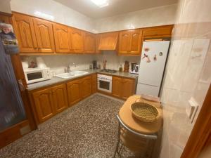 eine Küche mit Holzschränken und einem weißen Kühlschrank in der Unterkunft Carlota y Vaquero house in Vinarós + 8 Fotos