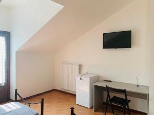 a room with a refrigerator and a desk with a television at La Chiocciola in Sale