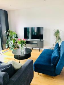 uma sala de estar com um sofá azul e uma televisão em Luxury 2 bedroom apartment 20 min from central London em Londres