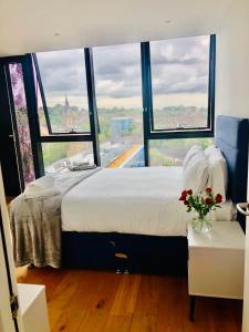 a bedroom with a large bed with a large window at Luxury 2 bedroom apartment 20 min from central London in London