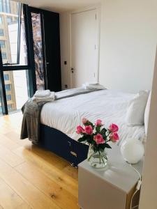 a bedroom with a bed with a vase of flowers on a table at Luxury 2 bedroom apartment 20 min from central London in London
