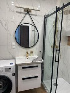 een badkamer met een douche, een wastafel en een spiegel bij Green Metropolis in Toruń