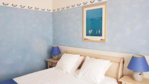 a bedroom with a bed with blue walls and two lamps at Hôtel de la Presqu'ile in Crozon