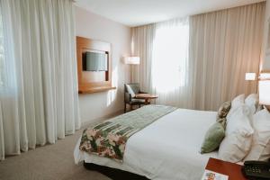 ein Hotelzimmer mit einem Bett und einem TV in der Unterkunft Howard Johnson Hotel Yerba Buena in Yerba Buena