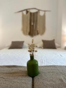 a green vase with a plant on a bed at Valente Rooms Kythira in Kythira