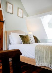 a bedroom with a bed with white sheets and pillows at Romantic Cotswold Cottage- dog friendly and village location in Mickleton