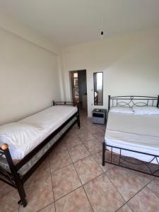 two beds in a room with a tiled floor at Dhoma Plazhi Husi in Himare