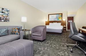 Courtyard by Marriott Cocoa Beach Cape Canaveral في كوكاو بيتش: غرفه فندقيه بسرير واريكه وكرسي