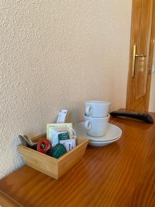 uma mesa de madeira com uma caixa de tesouras e uma chávena em Hostal Jose Mari em Ciudad-Rodrigo