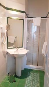 a white bathroom with a sink and a shower at Hôtel de la Presqu'ile in Crozon