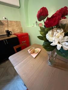 eine Vase mit roten und weißen Blumen auf dem Tisch in der Unterkunft Casetta Beatrice Tivoli Holiday Home in Tivoli