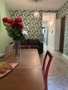 einen Tisch mit einer Vase roter Rosen und einem Laptop in der Unterkunft Casetta Beatrice Tivoli Holiday Home in Tivoli