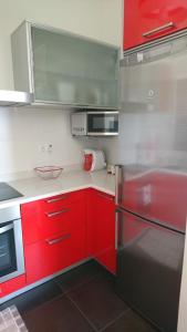 eine Küche mit roten Schränken und einem schwarzen Kühlschrank in der Unterkunft Ático con piscina en palmeira in Ribeira