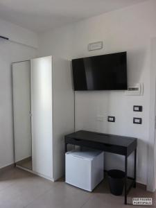 a room with a black desk and a flat screen tv at FAVARA Rooms in Portopalo