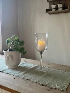 una vela en una copa de vino sentada en una mesa en Koselig gammelt hus på gård 