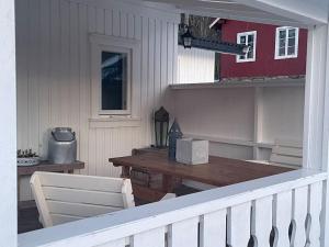 eine Veranda mit einem Holztisch und einem weißen Geländer in der Unterkunft Koselig gammelt hus på gård 