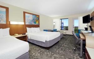 a hotel room with two beds and a desk at Courtyard by Marriott Cocoa Beach Cape Canaveral in Cocoa Beach