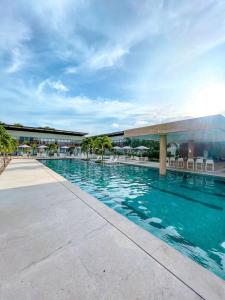 a swimming pool with chairs and a building at Flat Completo Pipa no condominio do lle de Pipa in Pipa