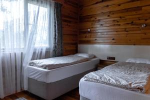 two beds in a wooden room with a window at Rüya Villen Park in Cıralı