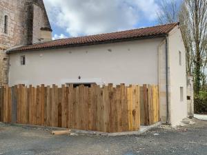a wooden fence in front of a white garage at P'tit gite du prieuré in Champdolent