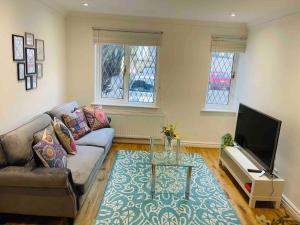 sala de estar con sofá y TV en Modern cosy house /free parking for two cars/ 3 minutes walk to the underground en Londres