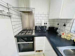 a kitchen with a stove and a sink at Modern cosy house /free parking for two cars/ 3 minutes walk to the underground in London