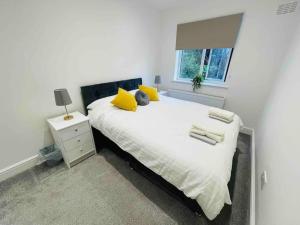 Un dormitorio con una cama con almohadas amarillas y una ventana en Modern cosy house /free parking for two cars/ 3 minutes walk to the underground en Londres