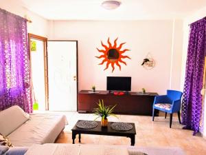 a living room with purple curtains and a sun on the wall at Blue Moon Apartments in Nea Michaniona
