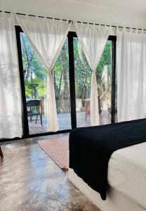 a bedroom with a bed and a large window at Pucté Bacalar in Bacalar