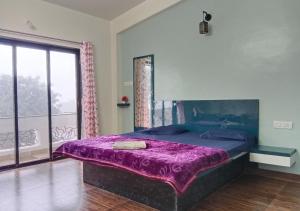 ein Schlafzimmer mit einem lila Bett und einem Fenster in der Unterkunft Bluebeli Mountain Villa By Holiday Villass in Mahabaleshwar