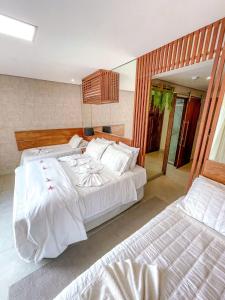 a bedroom with two beds with white sheets at Flat Completo Pipa no condominio do lle de Pipa in Pipa +25 photos